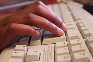 Black person's hands hovering over a computer keyboard