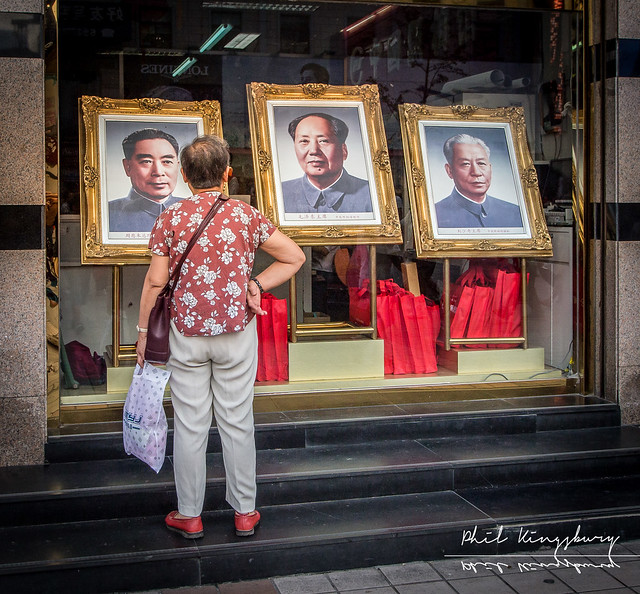 Admiring portraits of Zhou Enlai, Mao Zedong and Liu Shaoqi, previous Chinese Premiers, on Wangfujing Street, Beijing, China