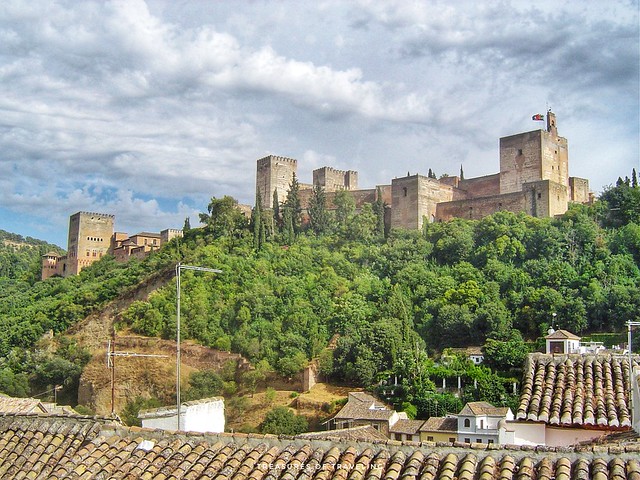 Looking up from the beautiful Arabic barrio called the Albaicín, you can see the majestic walls of the Alhambra! A palace and fortress complex located in Granada, Spain. The fortress has the backdrop of the Sierra Nevada Mountains in the background! This