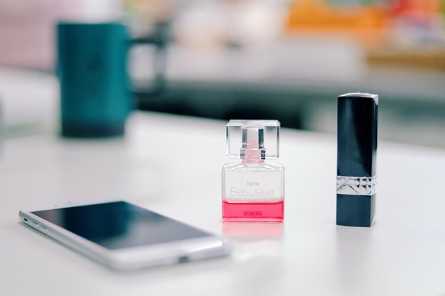smartphone on a table next to fragrance bottle and black lipstick bottle  - Credit to https://myfriendscoffee.com/