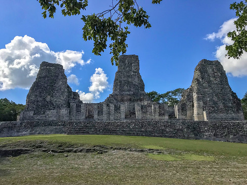 maya art mayan architecture archeology arc lintel rooms rocks ancient ruins old archeological site trees rainforest blue sky clouds grass three towers building front view xpuhil xpujil calakmul reserve campeche mexico pyramids structure 1 rio bec style