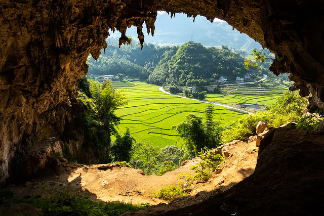 view from a cave onto the green fields below