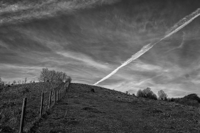 Hill, clouds and contrails