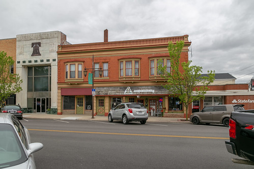 building structure historic napoleon ohio unitedstatesofamerica commercial henrycounty twostory brick classicalrevival orielwindows entablature colorful quoins splayed lintels storefronts altered cars street sidewalk clouds trees