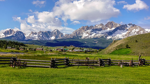 sawtoothmountains sawtooth mountain mountains stanley idaho landscape outdoor outdoors grass lawn field fence woodenfence farm implements sky clouds scenery scenic town smalltown valley river salmonriver snow snowcapped