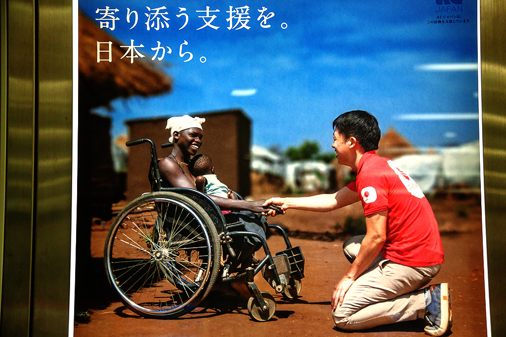African woman in a wheelchair shaking a Japanese man's hand--Osaka