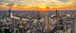 Panorama aerial view of Bangkok skyline and skyscraper with BTS skytrain Bangkok downtown in Thailand at sunset.