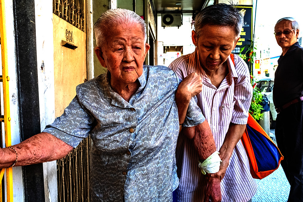 Old woman being helped by another old woman to walk on Jalan Bendahara--Malacca