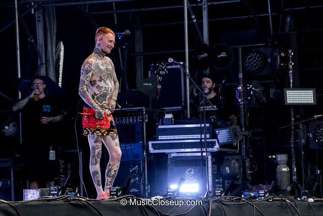 Frank Carter smiling and wearing only shorts, showing off tattoos all over his body