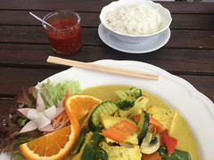 Healthy curry turmeric as vegan lunch, with rice, hot sauce, vegetables and salad, on a white plate with chopsticks