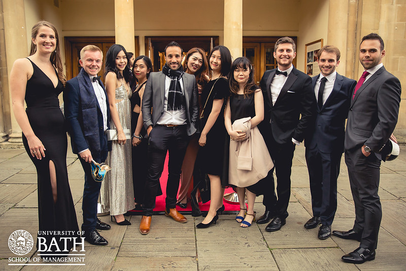 A group of students on the red carpet at a formal event. They are dressed in formal clothing and all smiling at the camera. 