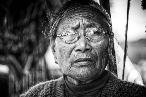 woman outdoors street portrait dharamsala uttar pradesh india tibet tibetan glasses nikkor 105mm head scarf dharma practitioner black white bw mono monochrome blanc et noir blanco y negro sony emount f25 manual focus a6000 alpha 6000 vintage lens shop lady portraiture