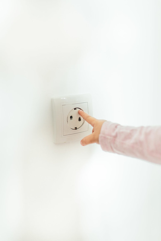 Child touching a plug socket cover with its finger