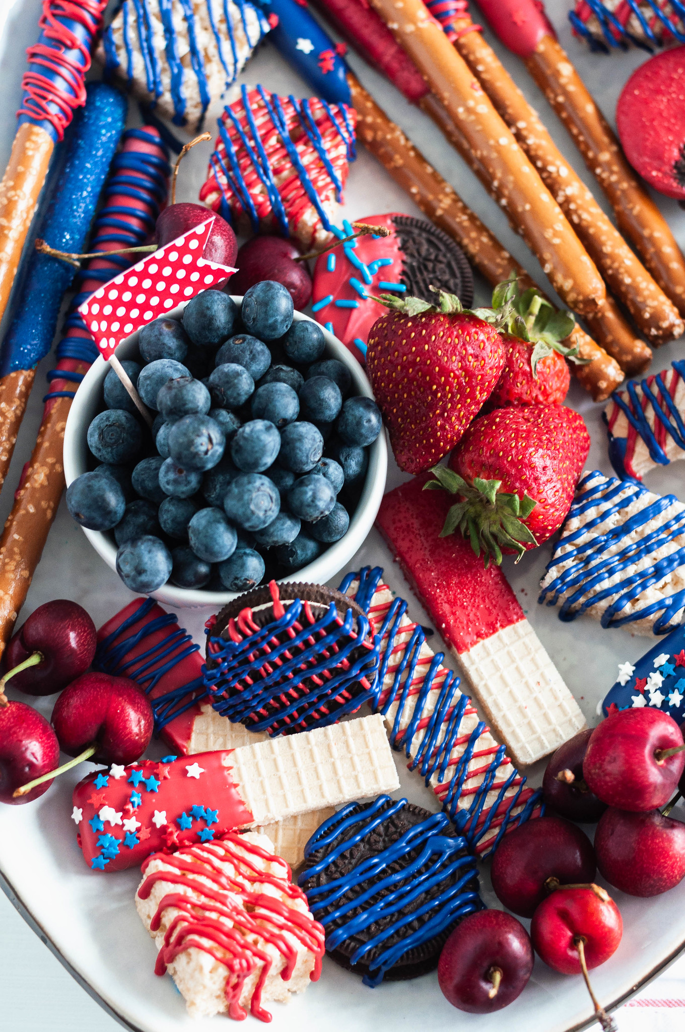 You'll be the hit of the 4th of July party when you show up with this Red White and Blue Dessert Board. Super simple to make with store-bought ingredients, some time and all your creative juices.