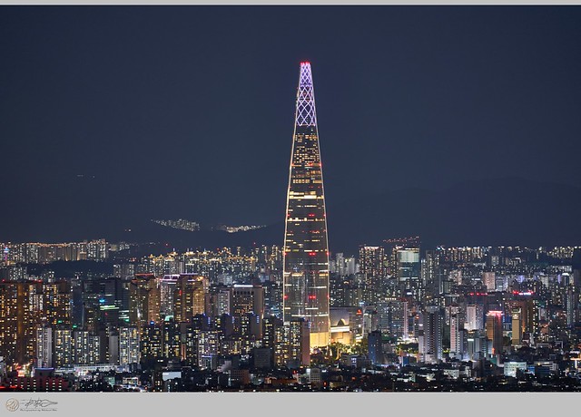 Colorful night view of Lotte Tower and surrounding city center.