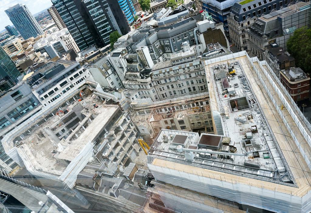 Looking down on a large building whose demolished top-levels are full of rubble and machinery