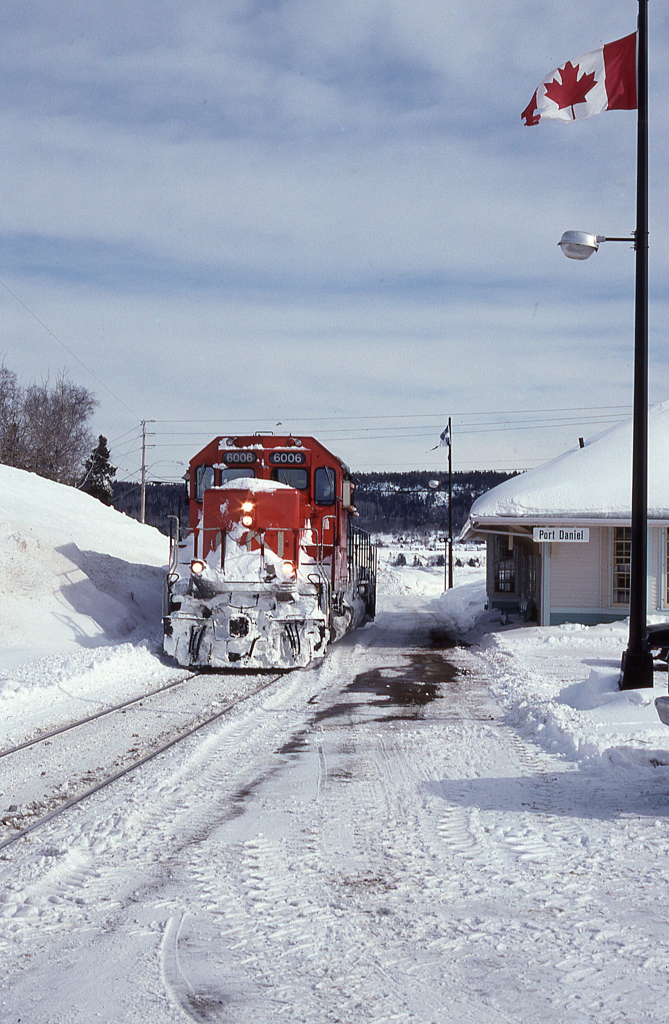 Happy Canada Day to all my friends north of the border.  On a much colder day then July 1st CN SD-40-2 # 6006 passes the station at Port Daniel, Quebec Feb. 17, 1995. The conductor has the window open to toss out a couple waters for us. 