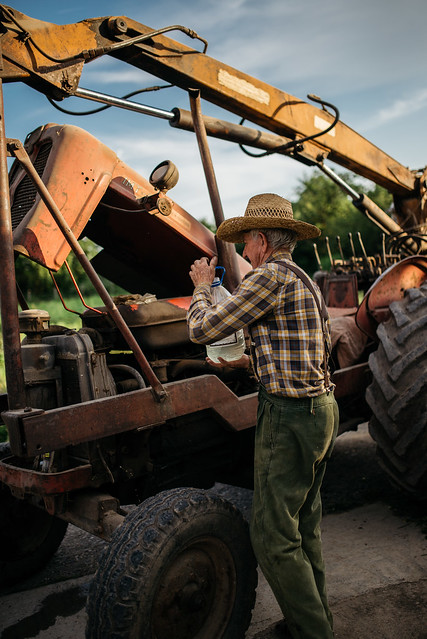 Alter Mann füllt Kühlwasser eines Traktors nach
