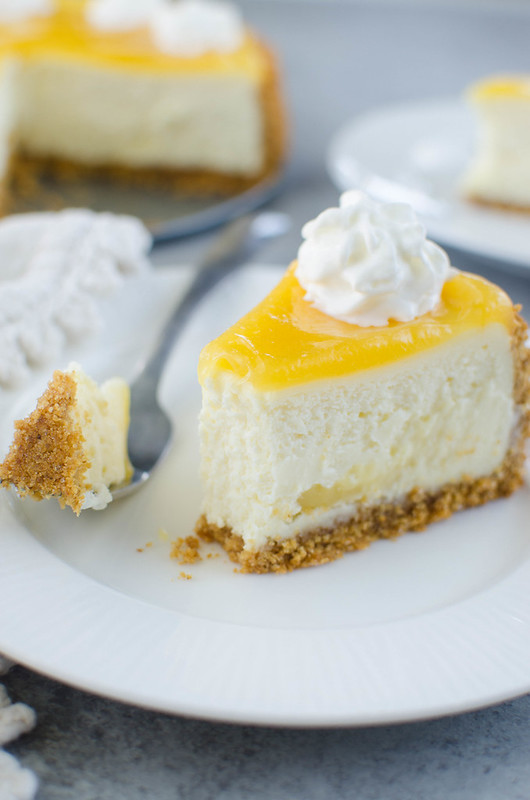 Lemon Bar Cheesecake - two of the best desserts in one! Creamy cheesecake with lemon curd swirls inside and topped with more lemon curd and whipped cream. 