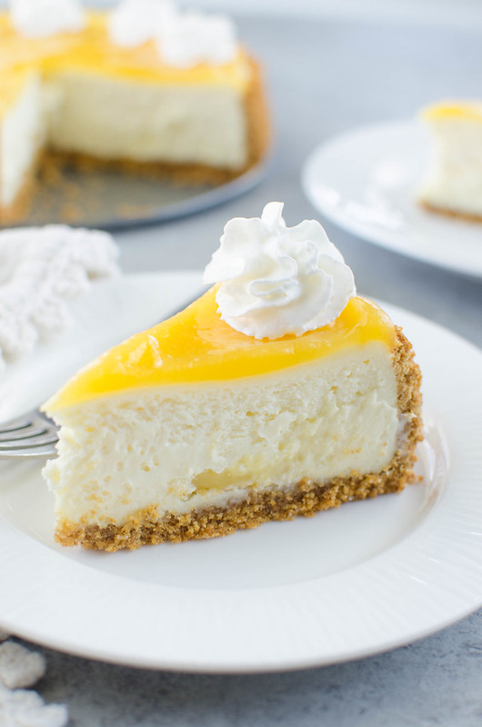 Lemon Bar Cheesecake - two of the best desserts in one! Creamy cheesecake with lemon curd swirls inside and topped with more lemon curd and whipped cream. 