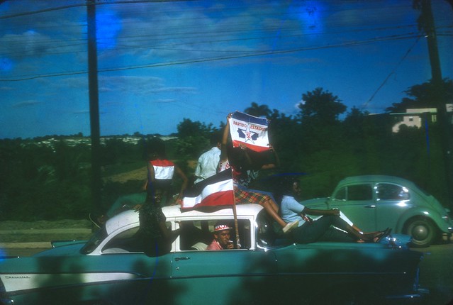 RW413--Man on hood of car with Partido Estadista flag, dec 64 copy