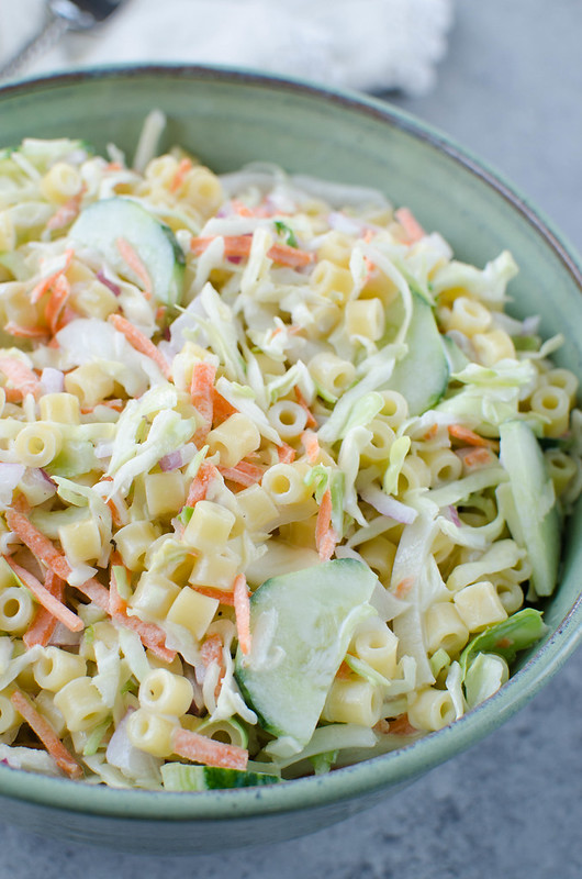 cold pasta salad made with ditalini pasta, cole slaw mix, sliced cucumbers, and red onion in a creamy dressing