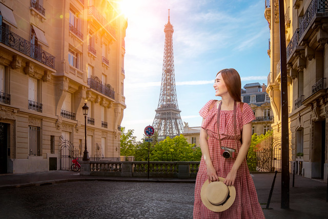 Asian girl walking in small paris street with view on the famous paris eiffel tower