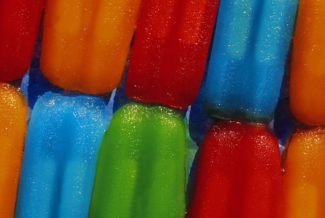 Rows of colorful melting popsicles laying out in the summer heat.