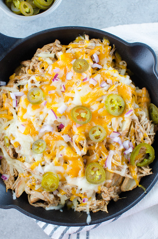 Pulled Pork Fries - crispy fries piled high with barbecue pulled pork, 2 kinds of cheeses, diced red onion, and jalapenos. Perfect for tailgating!