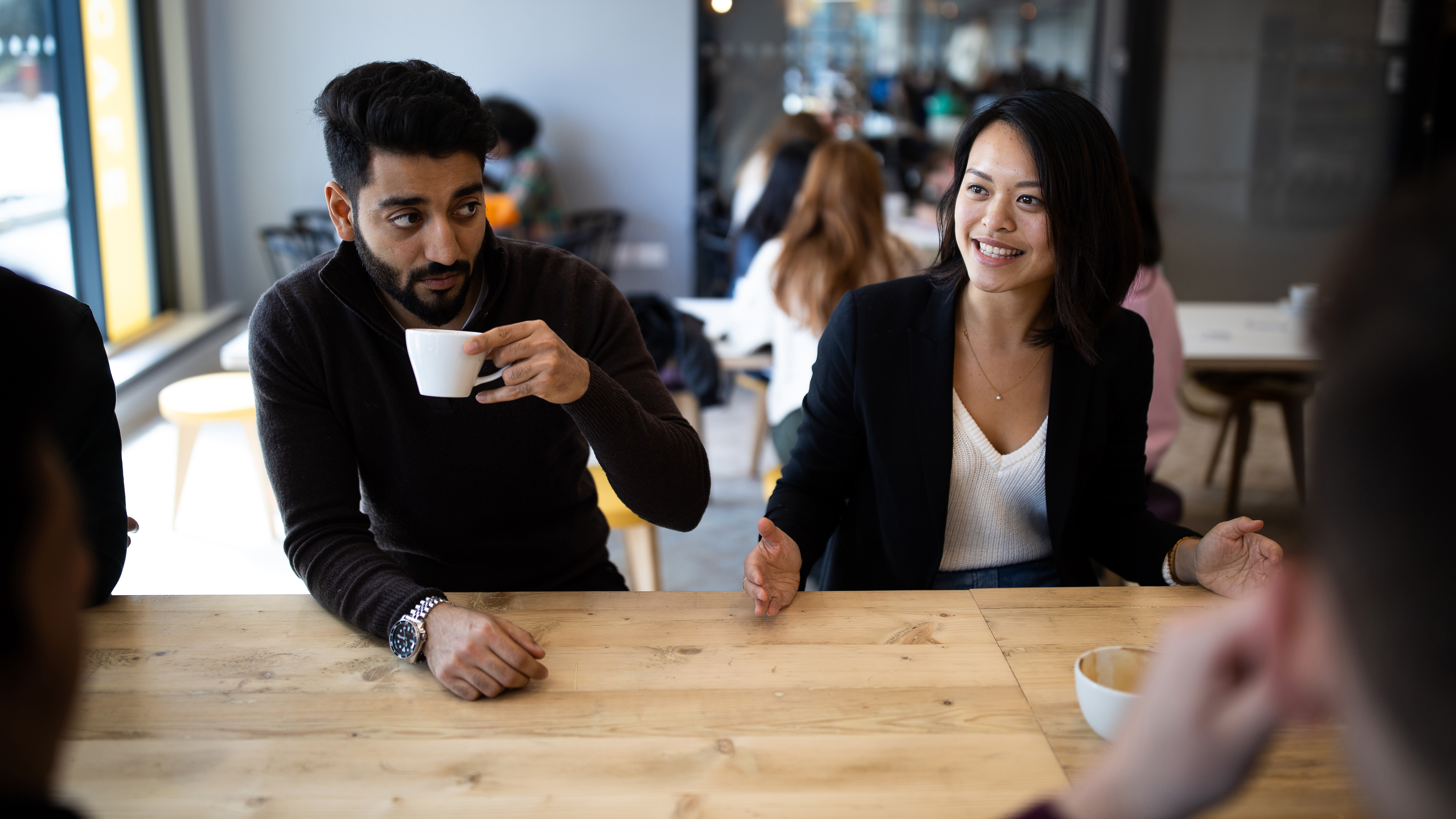 A man and woman having coffee with friends in a cafe