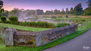 Misty dawn light on Stoke Charity village pond and St Michael's Church, Hampshire, UK