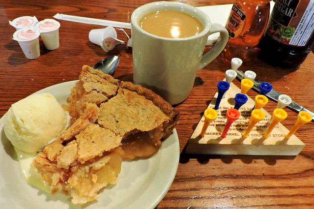 Old-fashioned apple pie with lard crust à la mode; cup of coffee with cream; and triangle peg game
