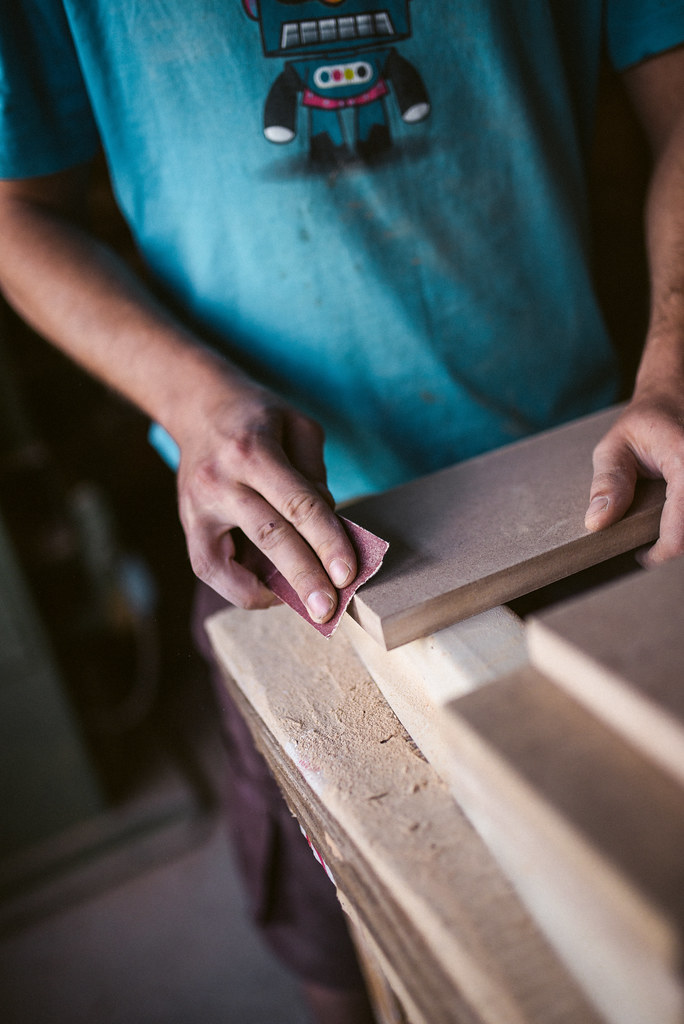 Hand sanding a wood board with sandpaper