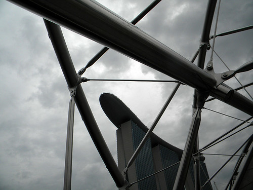 The pedestrian bridge and the ocean liner building silhouetted against a stormy sky in Singapore