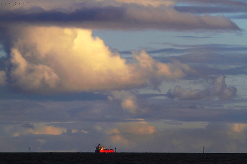 St Kilda Beach : Home Time by Clement Tang *, An overcast Winter evening: the sun lights up distant clouds and a cargo ship, the sea is dark, a fe