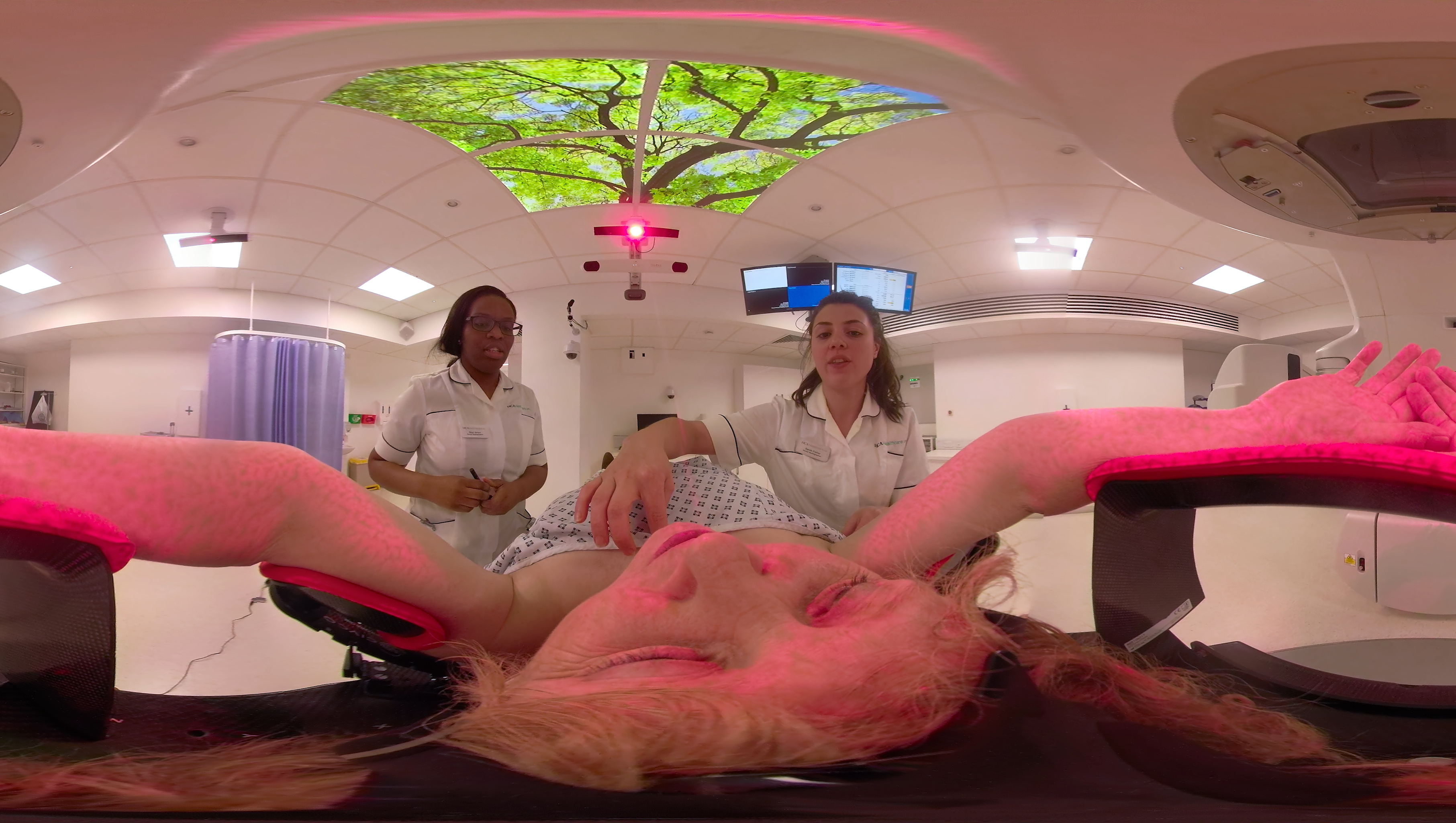 VR image of a patient having a CT scan, aided by two doctors
