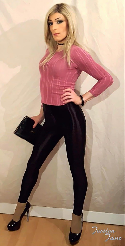 Shiny black disco pants and pink top with black choker, high heels and clut...