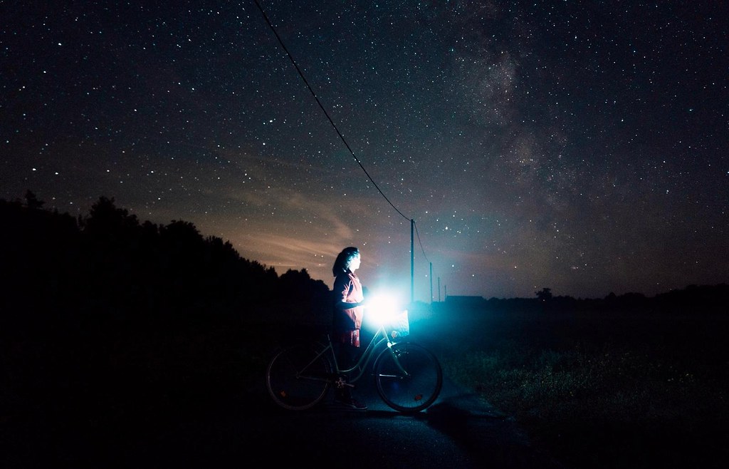 A girl with her bike beneath starry skies in Kihnu Island, Estonia [Photo by Kim Leuenberger]