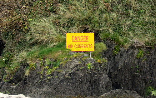 'Danger, Rip Currents' sign at a rocky beach near Galley Head in Ireland