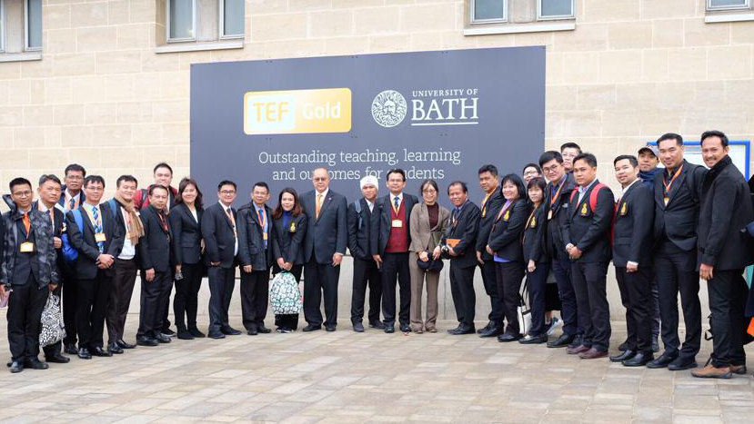 Senior managers from universities in Thailand stand in front of a University of Bath sign during their visit to the university.