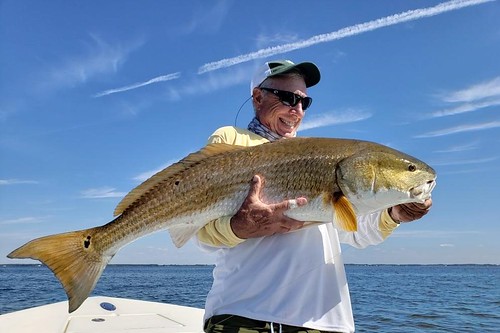 Photo of man with large red drum he caught and released