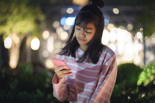 Young girl is texting at city night