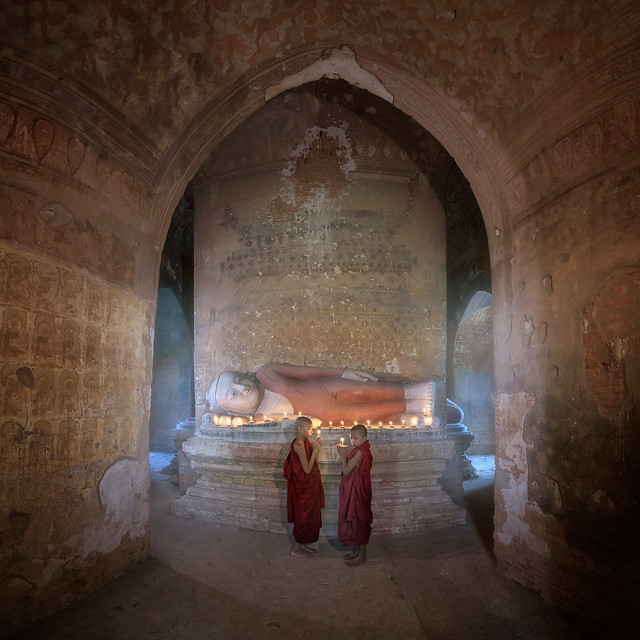 Two Monks Praying Inside Ancient Temple with the Reclining Buddha, Bagan, Myanmar