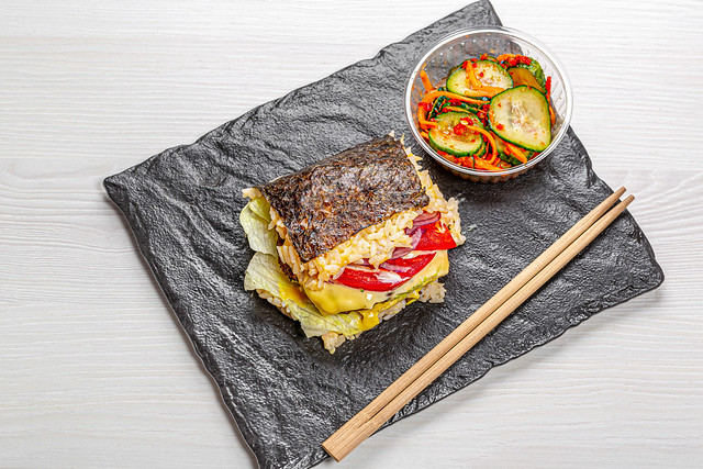 Sushi Burger auf schwarzem Hintergrund mit scharfem Gemüse Top-view