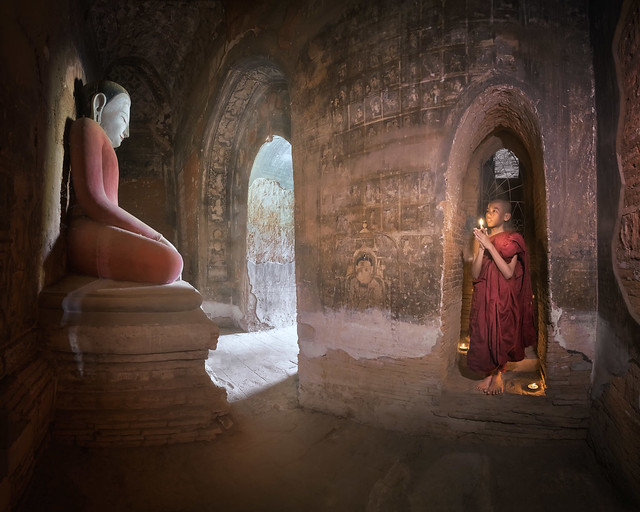 Monk Praying Inside Ancient Temple with the Seated Buddha, Bagan, Myanmar