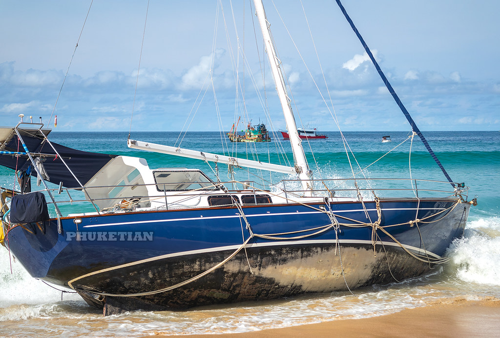 Disaster at sea. The wreck of a sailing yacht. Yacht was dropped from the anchor and thrown to the beach. Waves break the hull and fill it with water. Nai Harn Beach, Phuket, Thailand 25 October 2019
