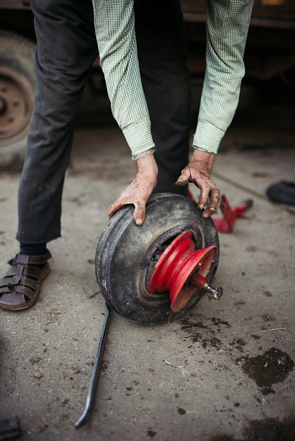 An old man taking a tire off an aluminium wheel