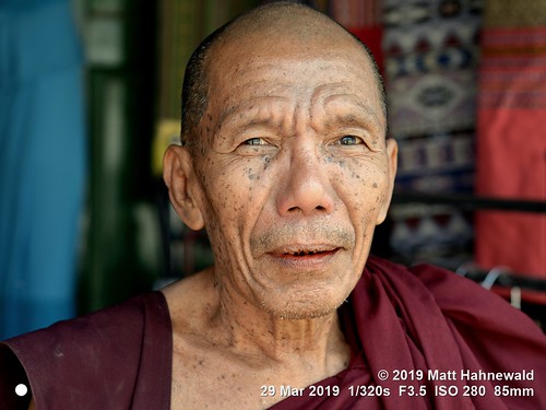 matthahnewaldphotography facingtheworld qualityphoto character head face eyes mouth badteeth livedinface wrinkles expression consensual respect dignity conceptual religion modesty ethnic local religious traditional cultural holy buddhism buddhistmonk maroonrobe bazaar shop monk kalaw shanstate myanmar burma asia asian burmese person one male elderly old man men detail background nikond610 nikkorafs85mmf18g 85mm street portrait closeup headshot indoor colour posing dignified shaved shorn bald paan arecanut betelnut lookingatcamera seveneighthsview