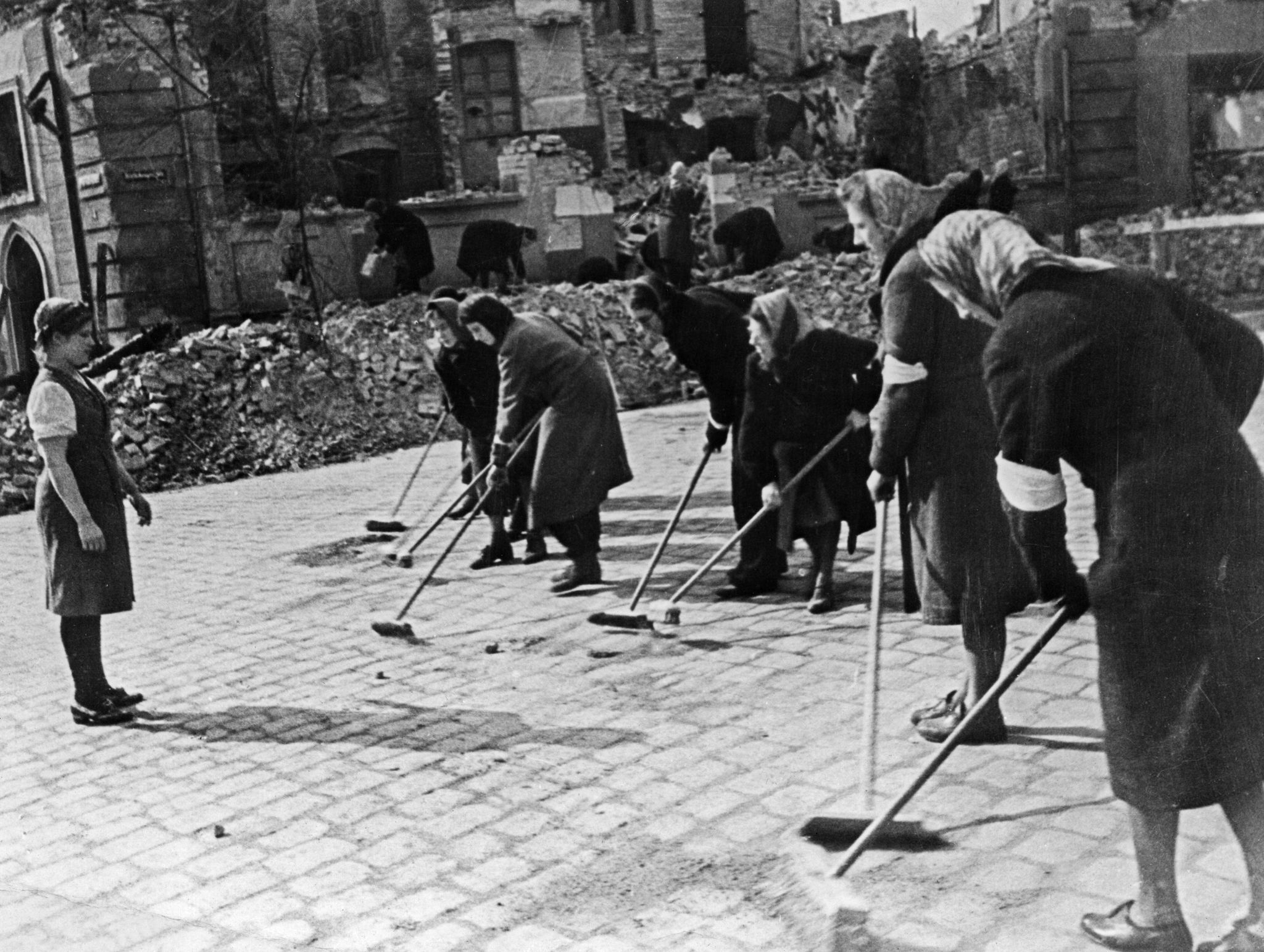 1945. Немецкие женщины, подметающие улицу Берлина после капитуляции под присмотром Маруси Кузнецовой, которая более двух лет провела в качестве подневольной работницы в Германии