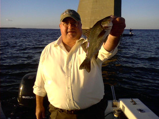Photo of man with a large white perch at the Bay Bridge. 